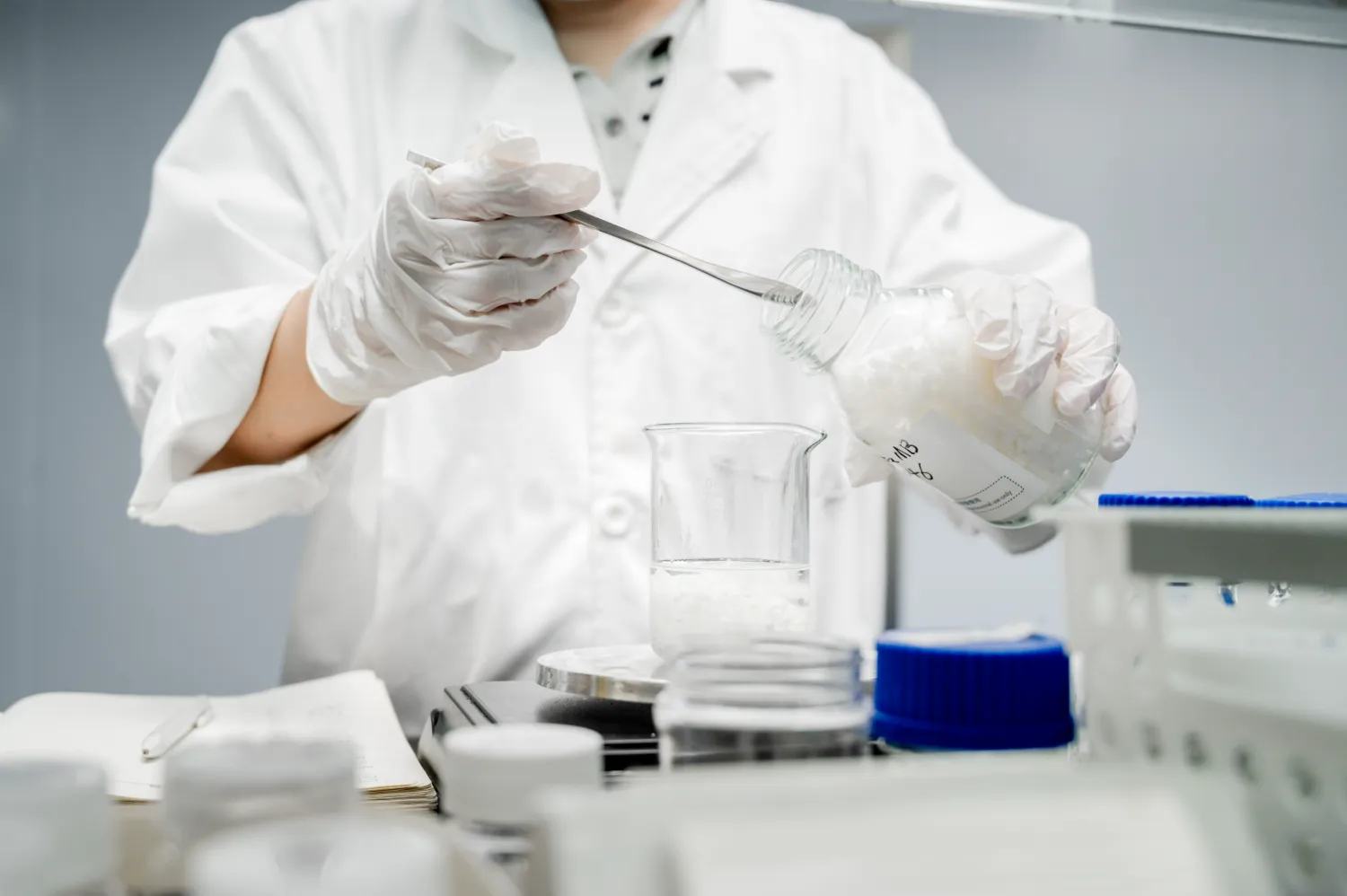 Lab technician pouring liquid from glass flask
