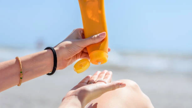 Woman applying sunscreen from a tube on a sunny beach